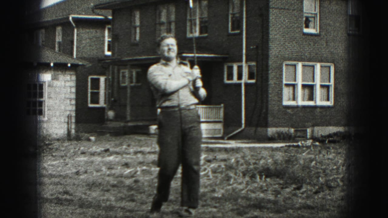 After the swing, the man faces the camera and smiles while holding the golf club in the New Cumberland yard.