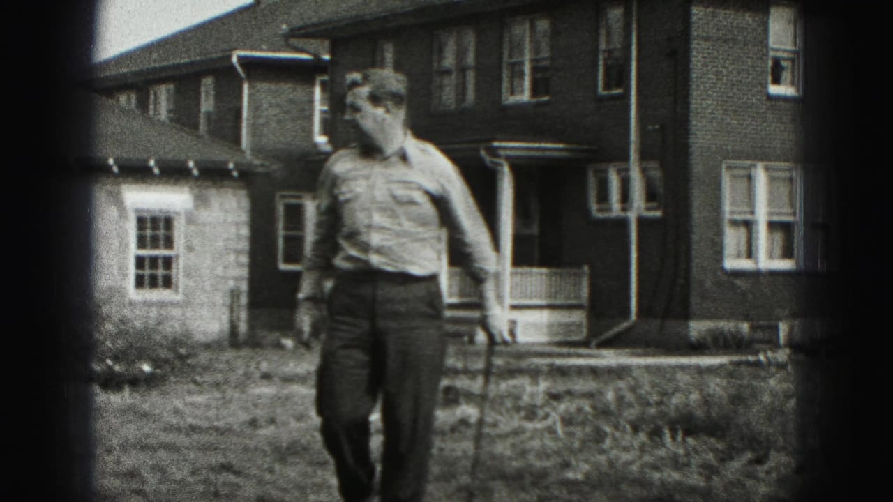 The man leans into his golf stance in a New Cumberland residential yard, with the brick house and porch behind him.