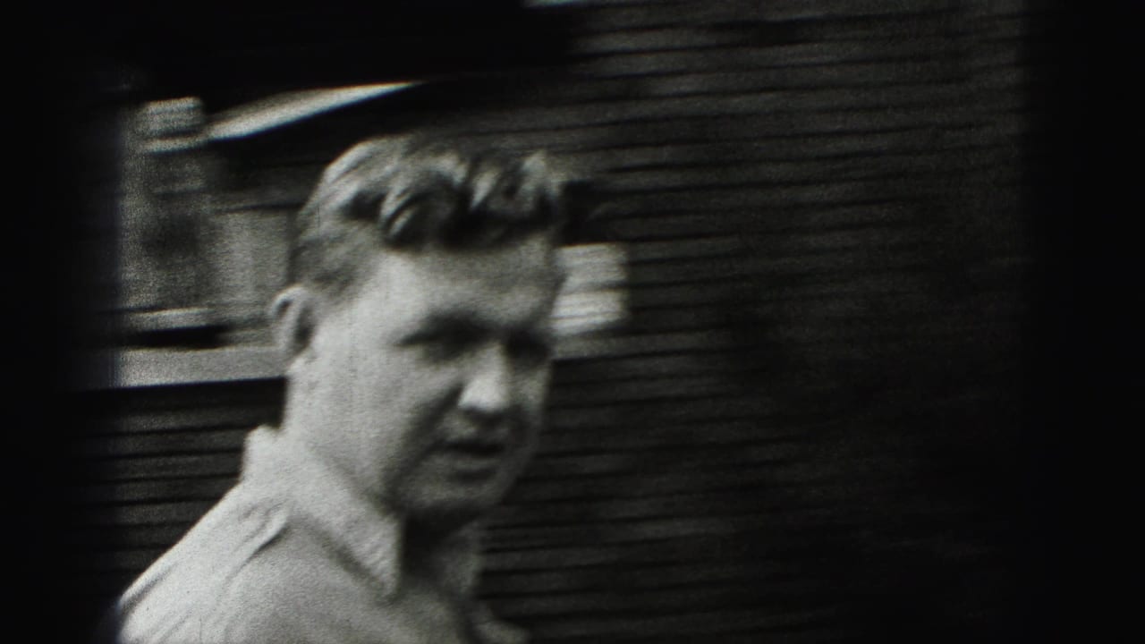 A closer 8mm view shows the man's face and upper body near a wood-sided exterior surface in the residential setting.