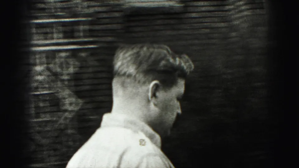 A young man in a light collared shirt passes a brick wall in 1946 New Cumberland 8mm home-movie footage.