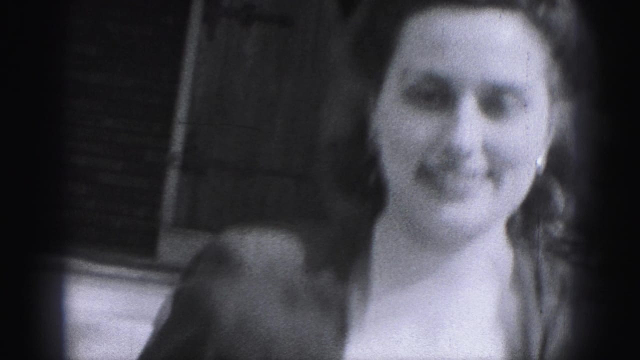Closer 1946 home-movie view of the woman smiling near a brick building exterior in New Cumberland, Pennsylvania.