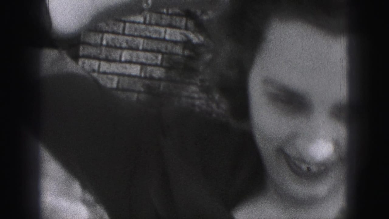 The woman appears to laugh or smile broadly near brickwork in the final close 1946 home-movie frame.