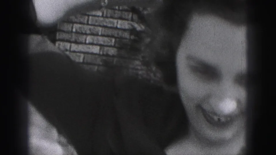 The woman appears to laugh or smile broadly near brickwork in the final close 1946 home-movie frame.