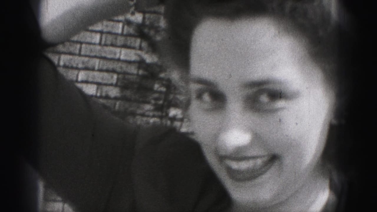 The young woman looks toward the camera with a playful expression while her arm remains raised against the New Cumberland brick-wall backdrop.