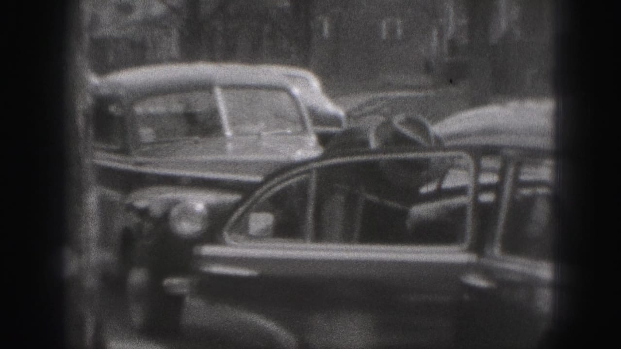 A woman in dark period clothing stands at an open automobile door on a 1946 New Cumberland residential street.