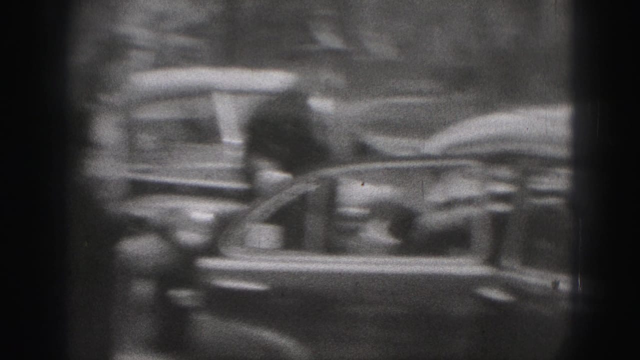 The camera catches motion blur as a woman moves beside the open car door during the New Cumberland street scene.