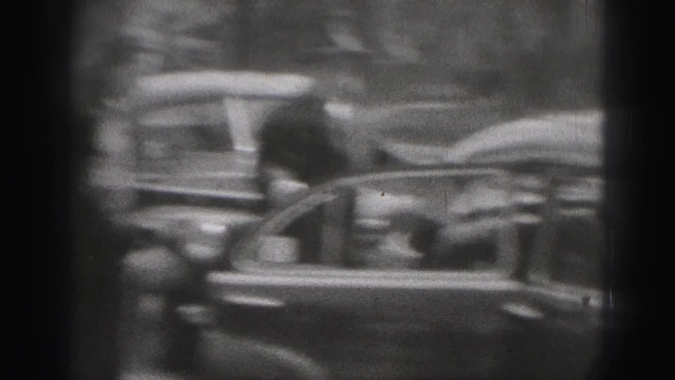 The camera catches motion blur as a woman moves beside the open car door during the New Cumberland street scene.