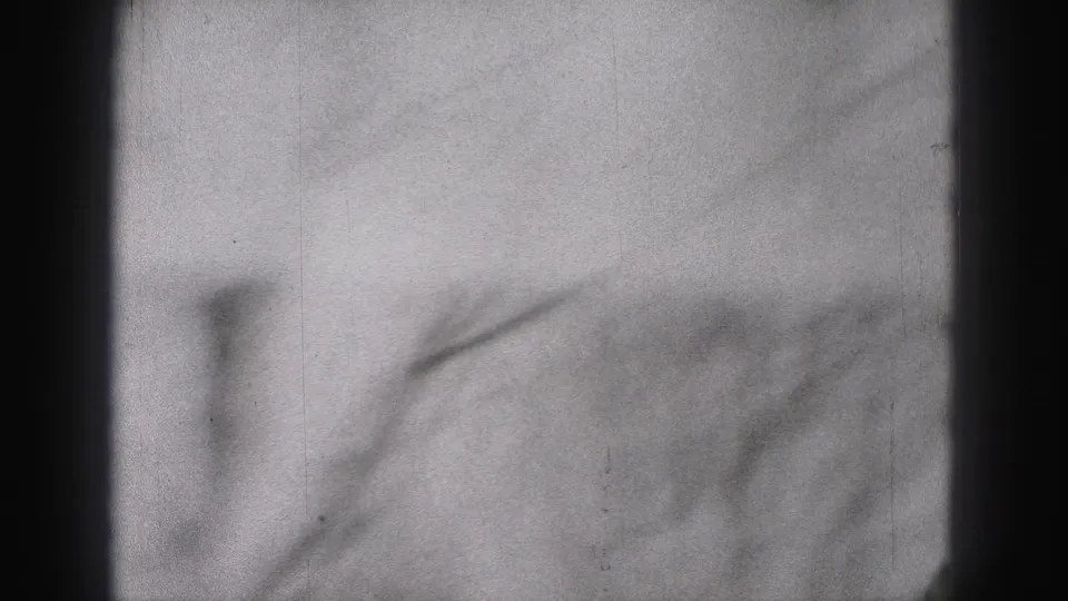 Soft, abstract 8mm frame from the New Cumberland 1946 clip, showing blurred street or sidewalk detail with visible film grain.