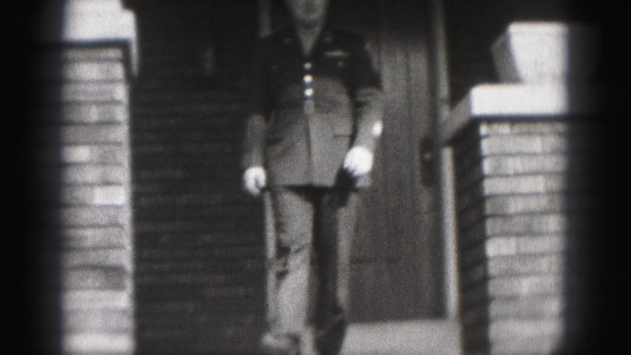 1946 New Cumberland home-movie frame of a uniformed man descending the steps of a brick house entrance.