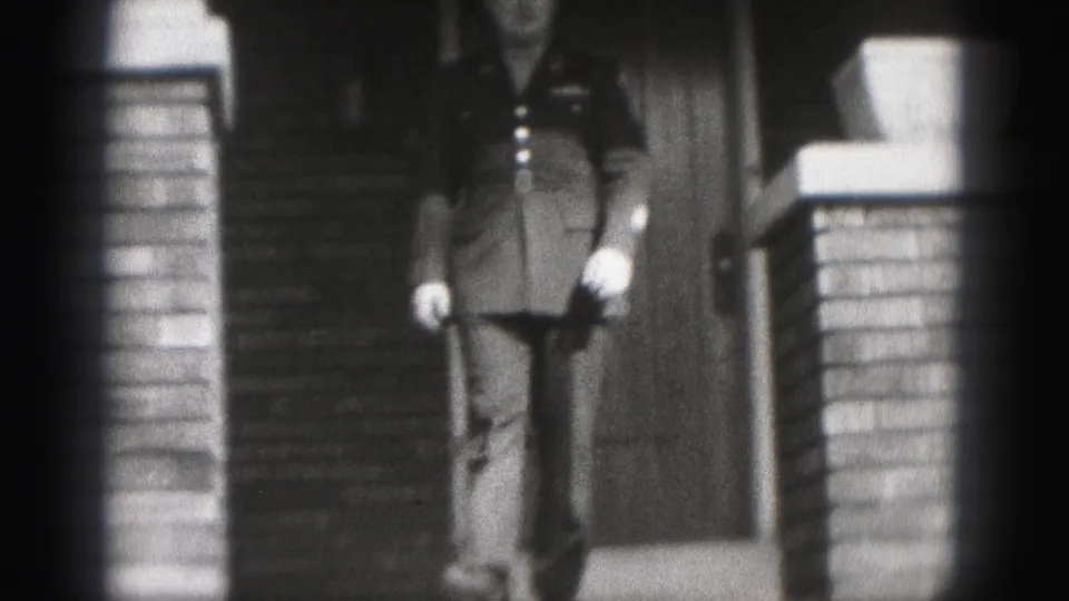 1946 New Cumberland home-movie frame of a uniformed man descending the steps of a brick house entrance.