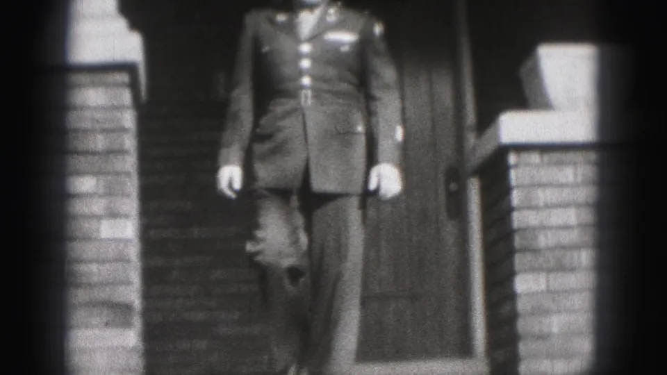 A uniformed adult man descends the front steps of a New Cumberland residence in 1946 black-and-white 8mm footage.