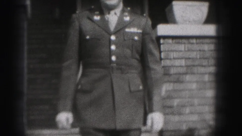 A closer black-and-white frame shows the uniform jacket and brick porch detail as the man nears the camera.