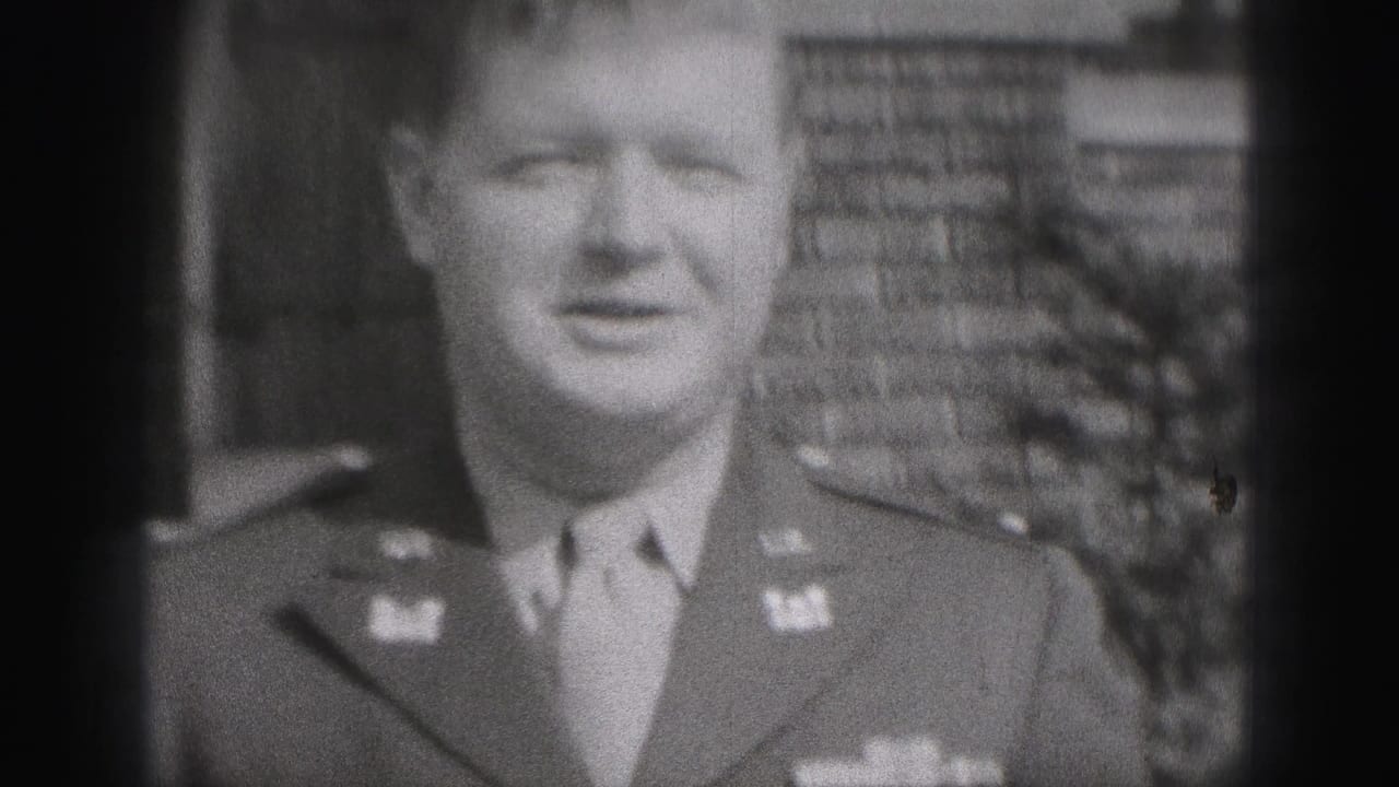 Close view of a smiling man in military uniform outside a brick building.