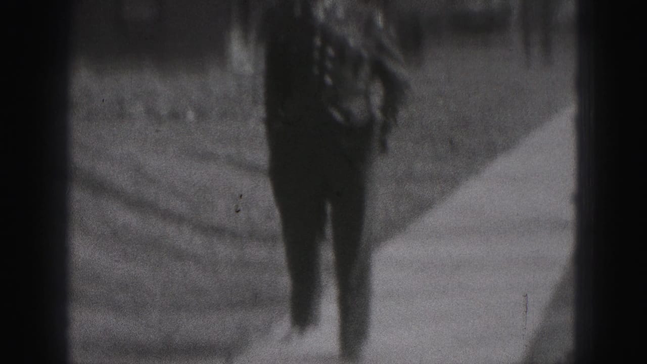 A rear view shows the formally dressed man moving away along a narrow sidewalk in the 1946 New Cumberland home-movie scene.