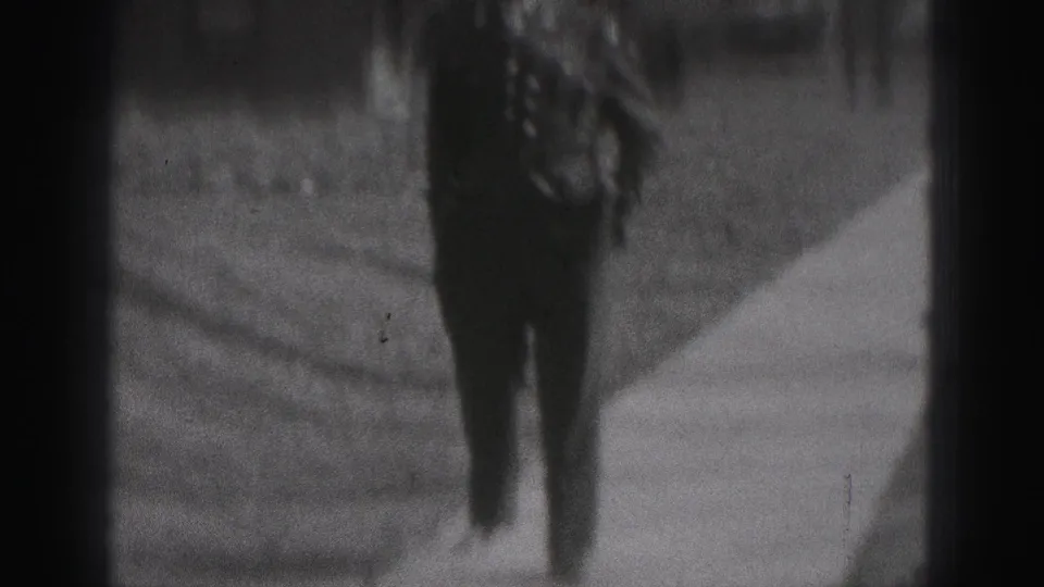 A rear view shows the formally dressed man moving away along a narrow sidewalk in the 1946 New Cumberland home-movie scene.