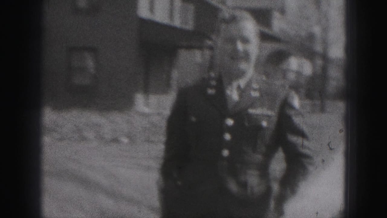 The man faces the camera more closely, with buttons and uniform-like details visible against a residential New Cumberland backdrop.