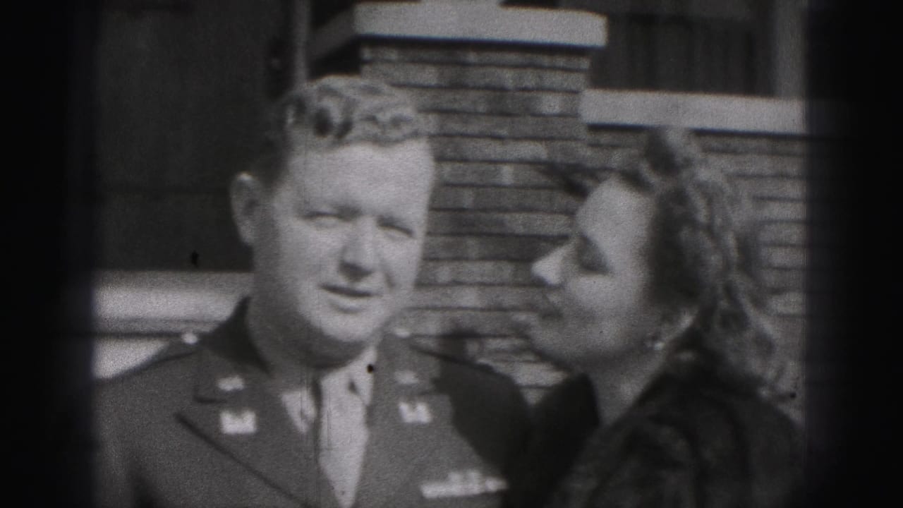 The uniformed man faces the camera while the woman leans toward him, a tender couple pose in the 1946 New Cumberland home-movie scene.