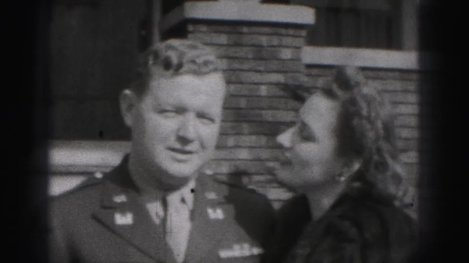 The uniformed man faces the camera while the woman leans toward him, a tender couple pose in the 1946 New Cumberland home-movie scene.