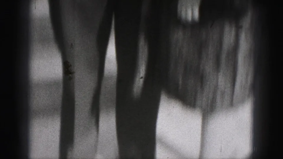 Soft-focus black-and-white 8mm frame showing shadowed exterior surfaces near the brick house setting in the New Cumberland, Pennsylvania clip.