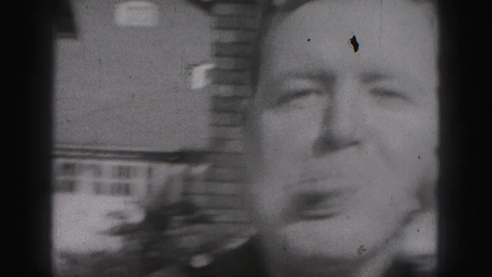 Black-and-white 1946 home-movie frame from New Cumberland showing a man near the camera making a playful expression as a woman appears at the edge.