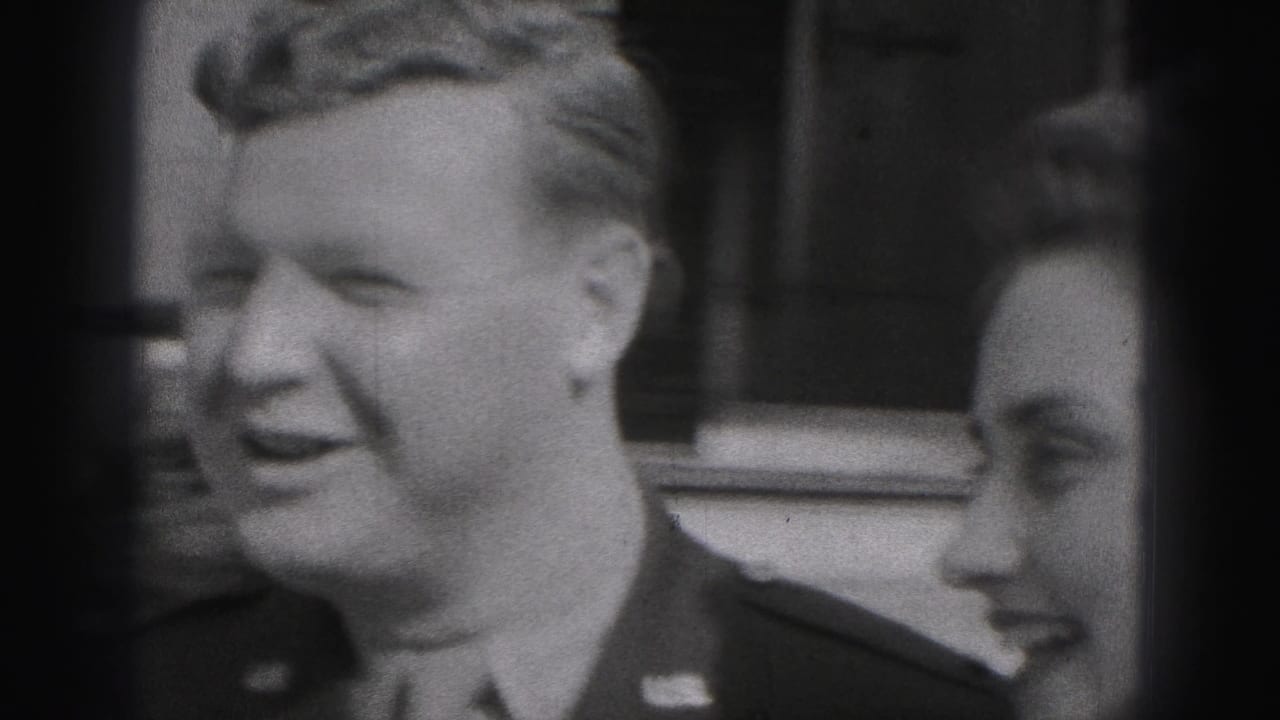 Black-and-white 1946 New Cumberland frame showing a smiling uniformed man standing beside a woman outdoors by a brick exterior.
