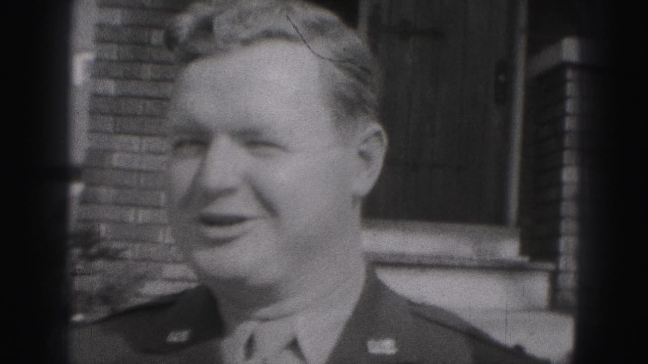 Black-and-white 1946 New Cumberland home-movie frame with a uniformed man smiling near a brick building and dark doorway.