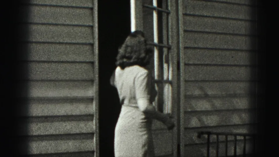 In New Cumberland, Pennsylvania, a woman in a 1940s-style dress is seen from behind at a glass-paneled house door.
