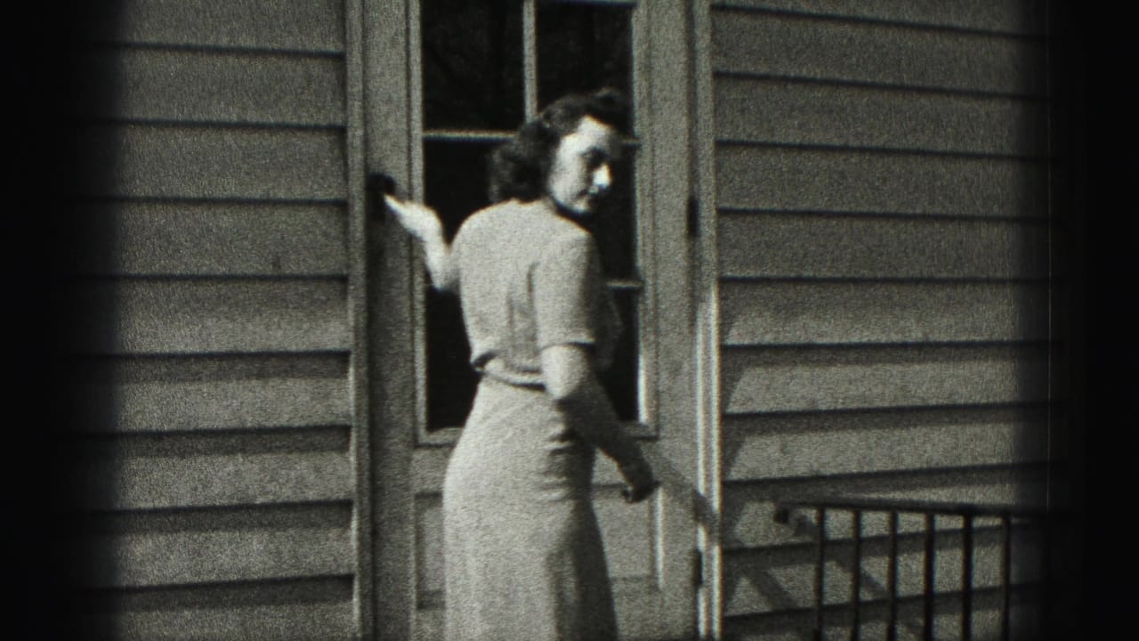 Woman turns back near the open door with one hand close to the frame.
