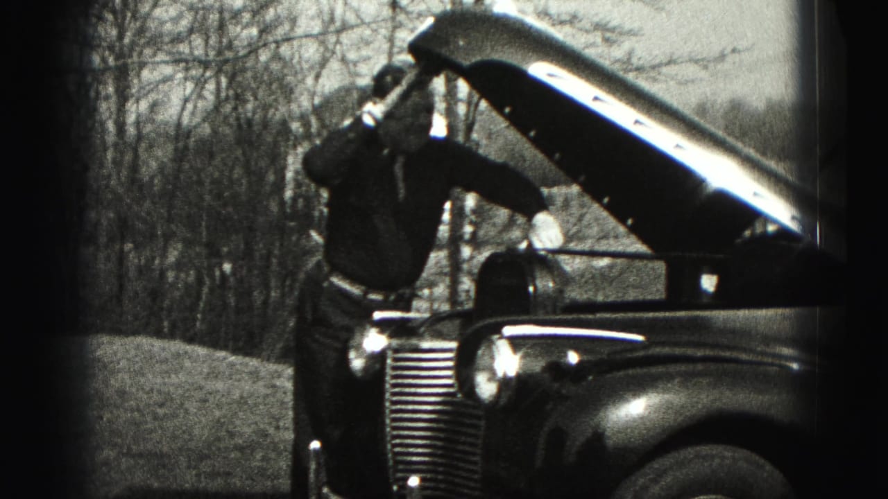 In New Cumberland, Pennsylvania in 1946, a man works at the open hood of a vintage automobile beside bare trees.