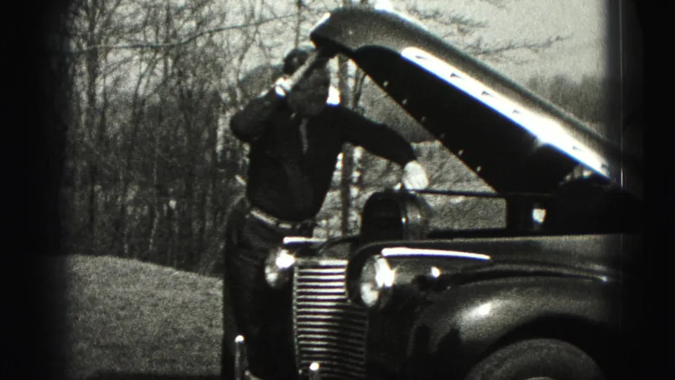 In New Cumberland, Pennsylvania in 1946, a man works at the open hood of a vintage automobile beside bare trees.