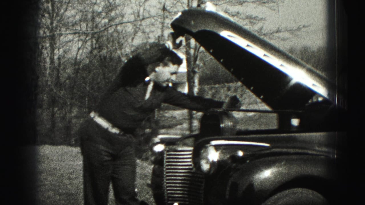 In 1946 New Cumberland, Pennsylvania footage, a suited man bends over the open hood of a 1940s automobile beside bare trees.