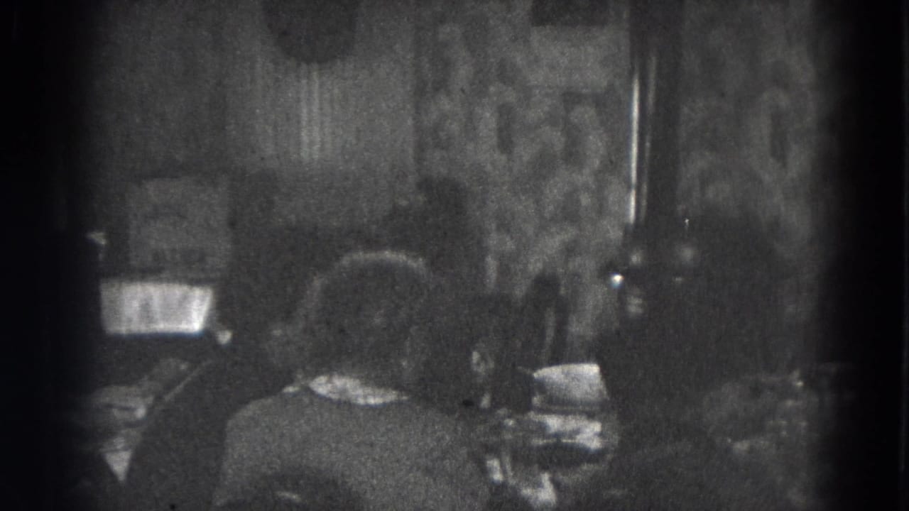 Adults appear at a dining table inside a Lincoln, Nebraska home, with patterned wallpaper and dishes visible.