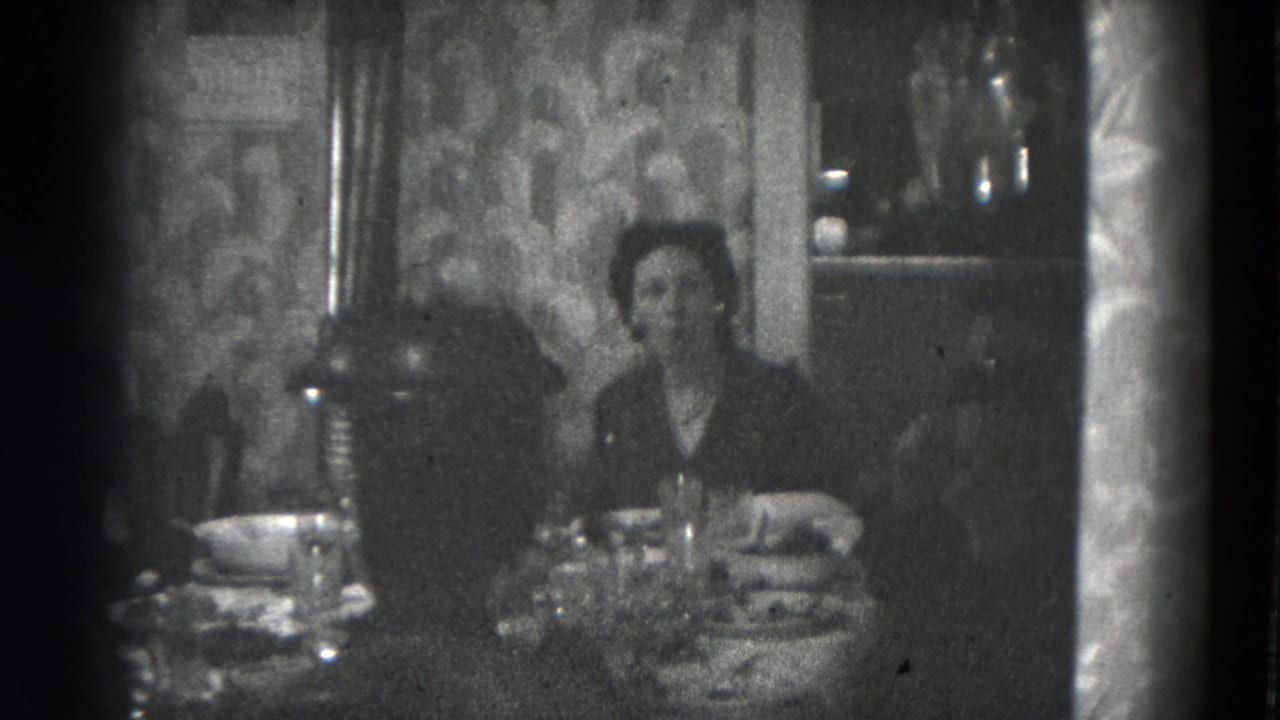 A woman faces the camera from a dining table in a private Lincoln home, with dishes and a lamp visible.
