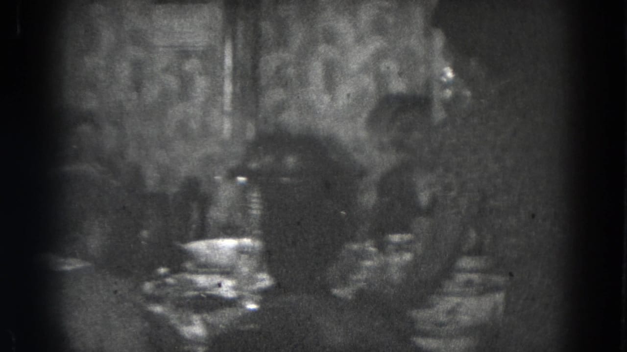 1947 Lincoln, Nebraska home-movie frame showing family members at a dining table in a dimly lit room.