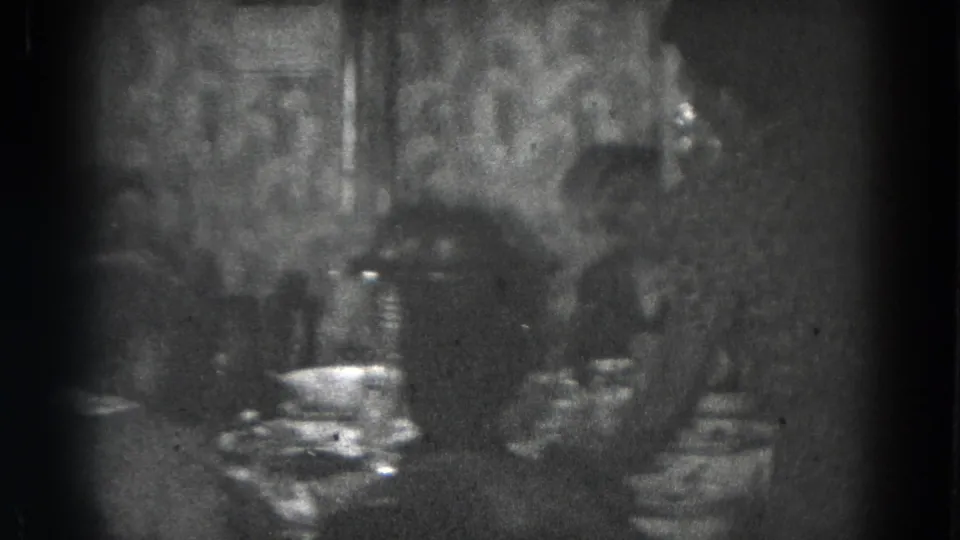 1947 Lincoln, Nebraska home-movie frame showing family members at a dining table in a dimly lit room.