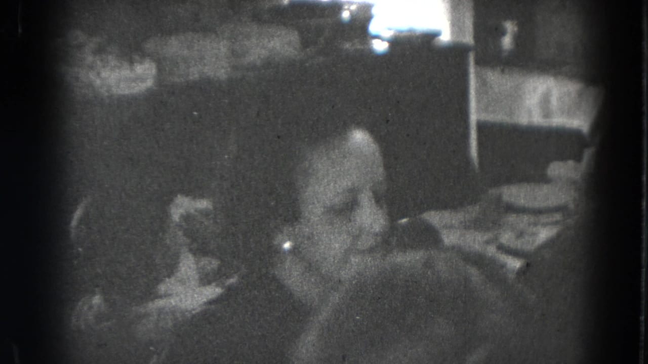 A seated adult is visible near a set dining table in grainy 1947 Lincoln, Nebraska home footage.