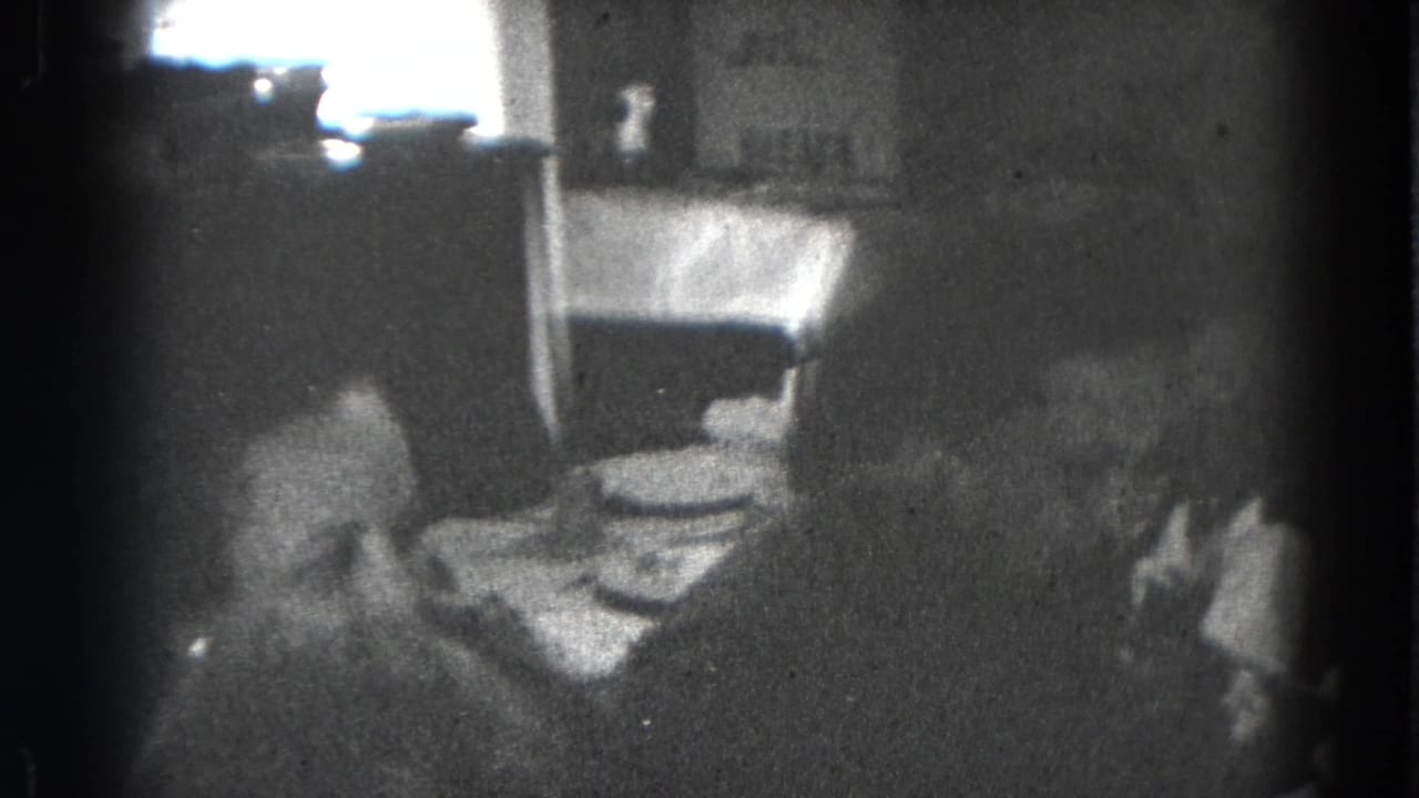 Two family members appear near the dining table in a dark 1947 Lincoln, Nebraska home-movie frame.