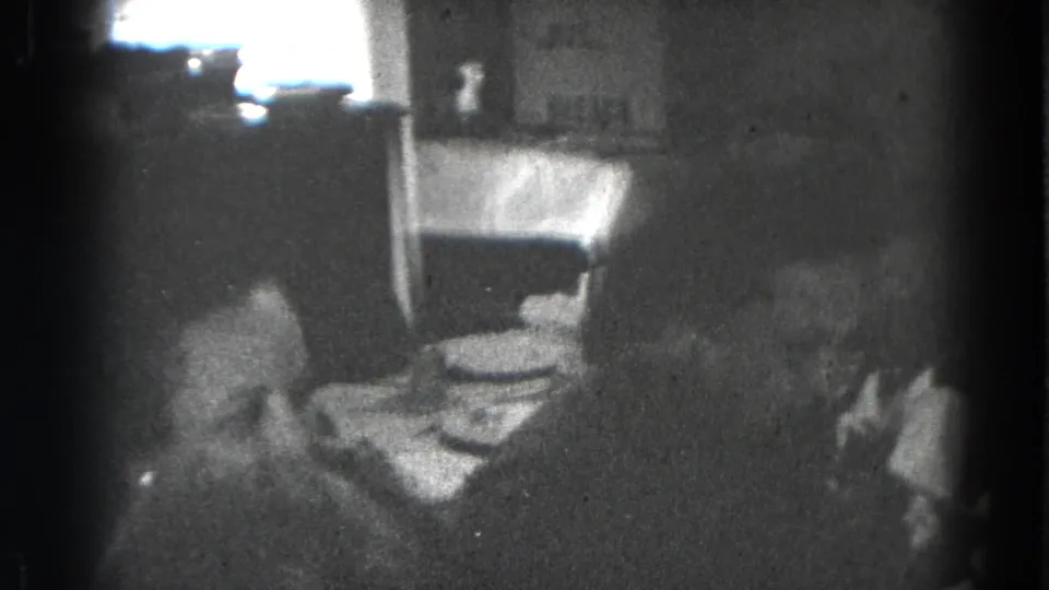 Two family members appear near the dining table in a dark 1947 Lincoln, Nebraska home-movie frame.