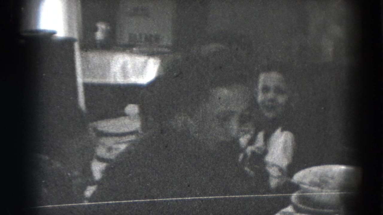 1947 Lincoln, Nebraska home-movie frame showing adults gathered around a dining table with plates and serving dishes.