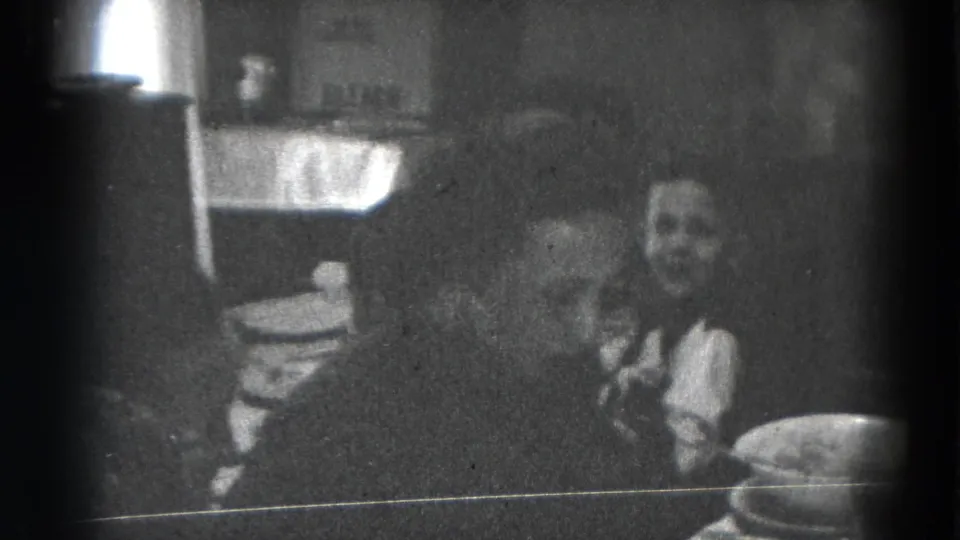 1947 Lincoln, Nebraska home-movie frame showing adults gathered around a dining table with plates and serving dishes.