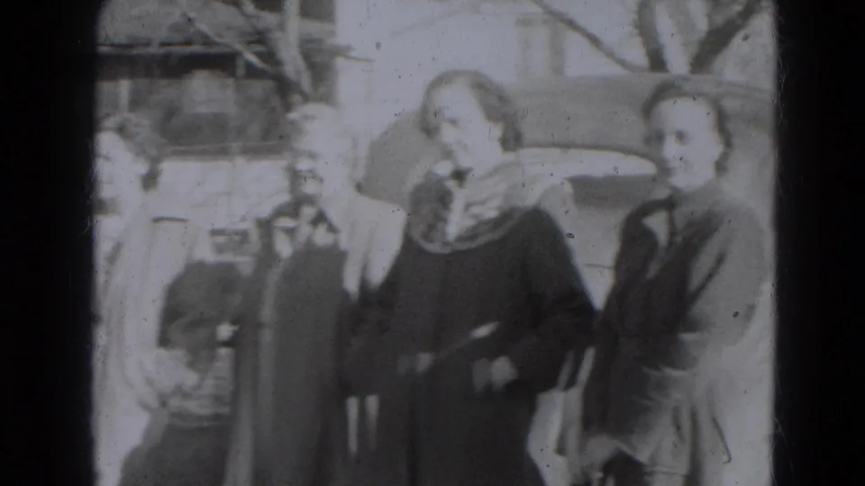 Women in coats and scarves face the camera as other adults and parked cars remain visible in the 1947 Lincoln street scene.