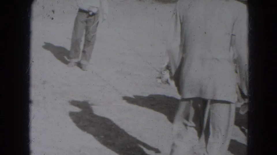 1947 Lincoln, Nebraska home-movie frame showing adults partly cropped on a sunlit open surface with strong shadows.