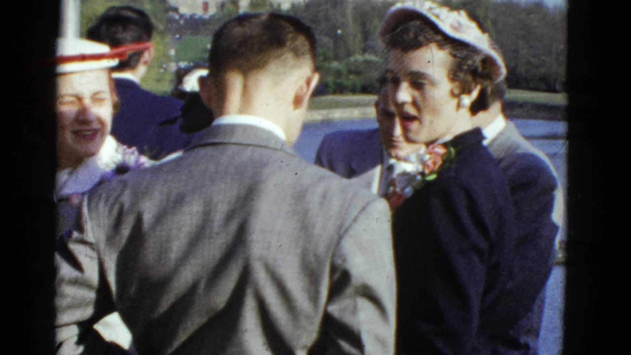 1951 Boston home-movie frame showing well-dressed adults talking outdoors in a park-like setting.