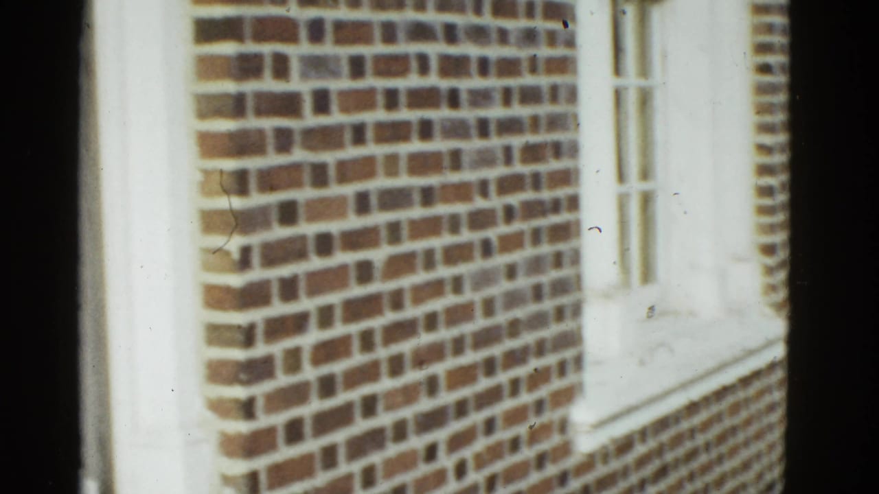 Brick building exterior with white trim and windows, partially obscured by dark film edge.