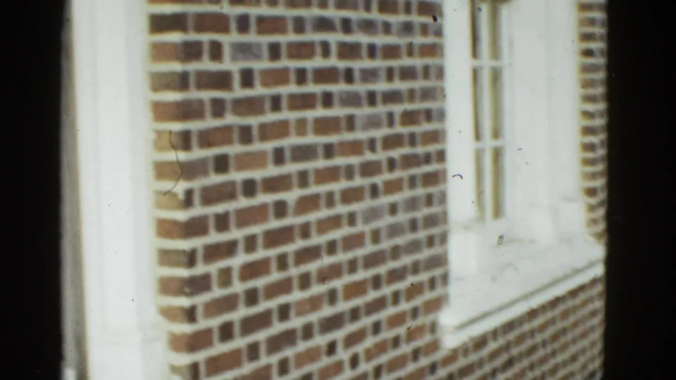 A brick building exterior with white trim and narrow windows appears in the 1951 Boston home-movie frame.