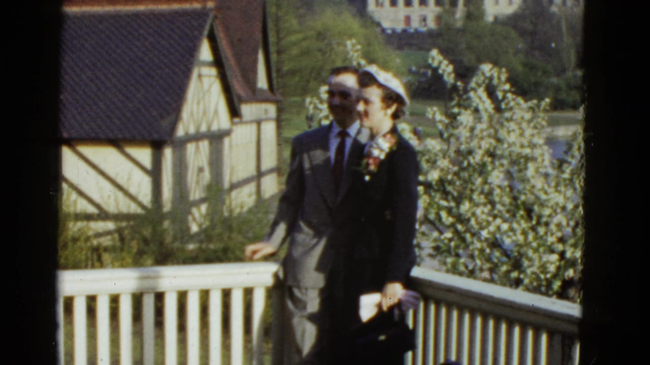 The couple remains on the balcony as the man rests near the railing.