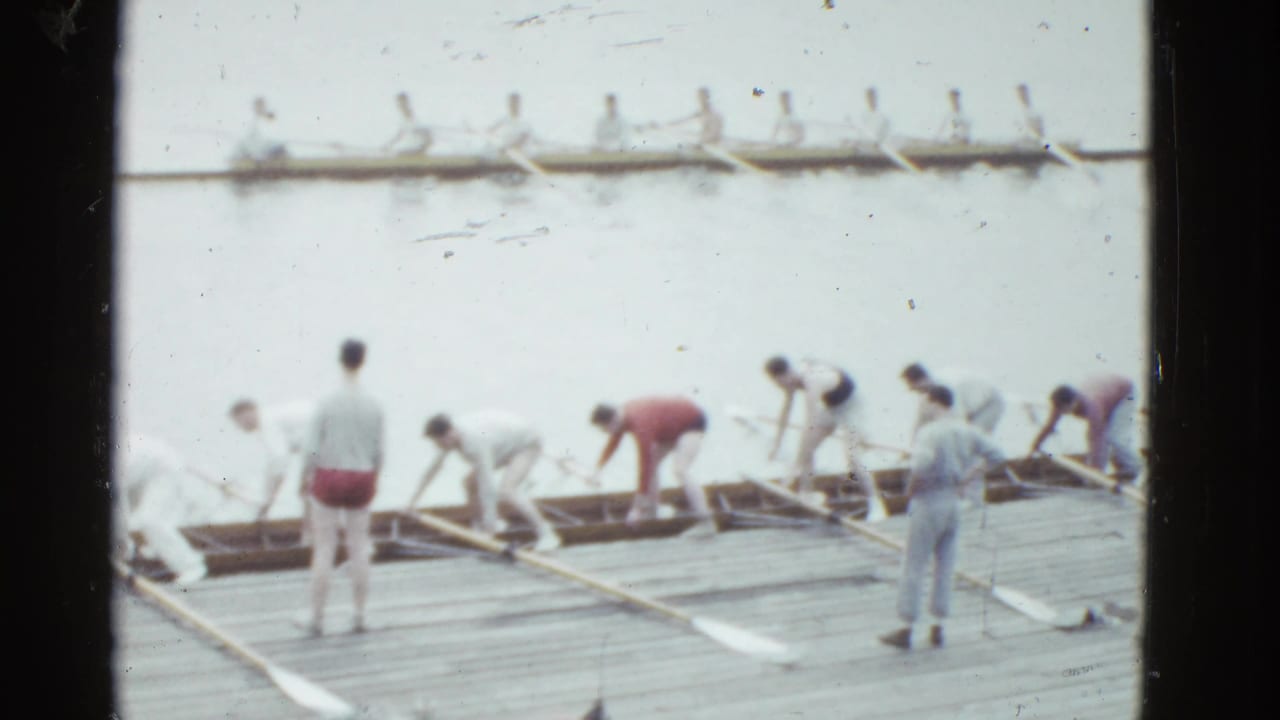 1951 Boston rowing scene with people handling oars and long shells beside a wooden dock, seen in soft 8mm color.