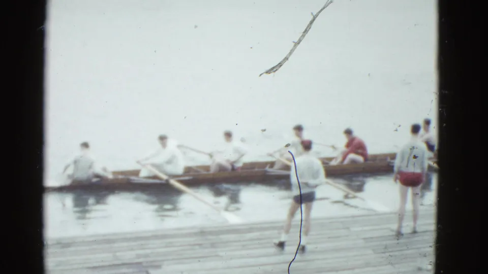 1951 Boston footage shows a rowing crew in a wooden shell on the river, with observers or team members standing on the dock.