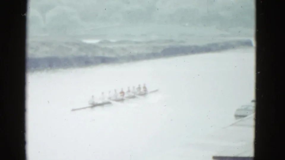 The final frame shows the crew boat small in the distance on calm water, with Boston-area location supported by clip metadata.