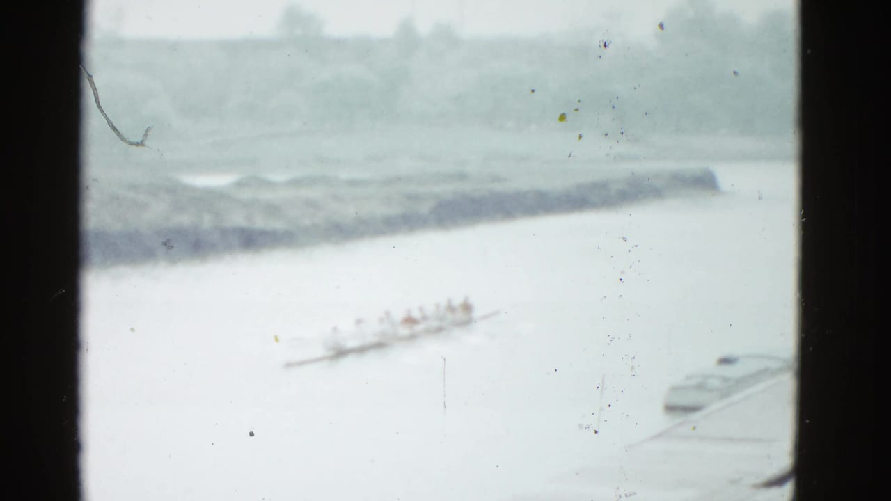 A distant rowing crew continues across the river in the 1951 Boston footage, with shoreline and small boats faintly visible.